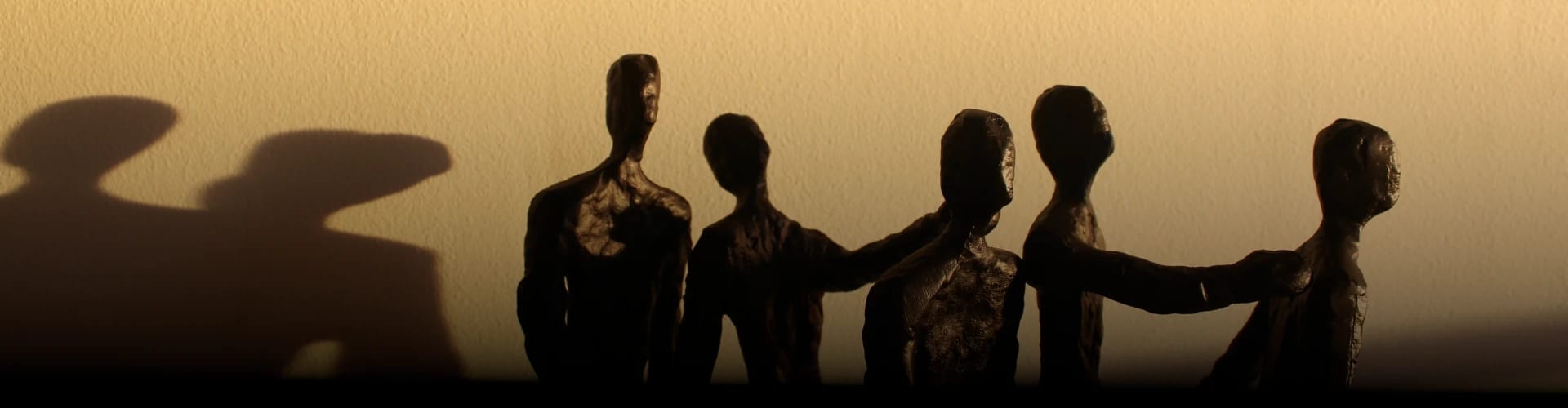 A shadowy image of scultures of humans working together as a group.