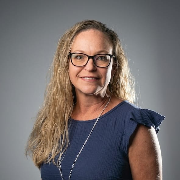 Image of a woman with long blonde hair and thick framed glasses.